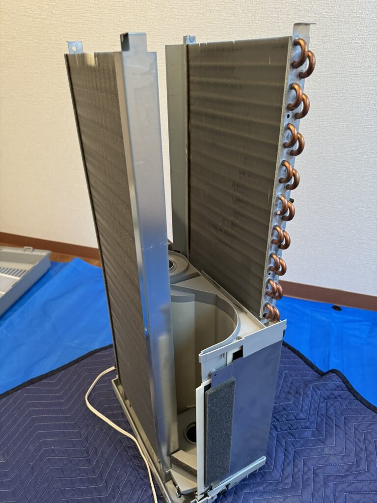 窓用エアコンを分解してファンとケーシングを外して熱交換器が見える状態にした本体