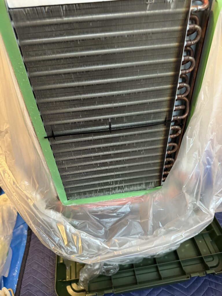 分解して洗浄出来るように電装部が濡れないように養生した窓用エアコン本体
