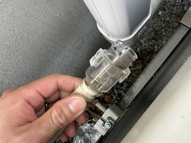 エアコンのドレンホースの先に付いた防虫弁を外しているところ。中に汚れがたまっている